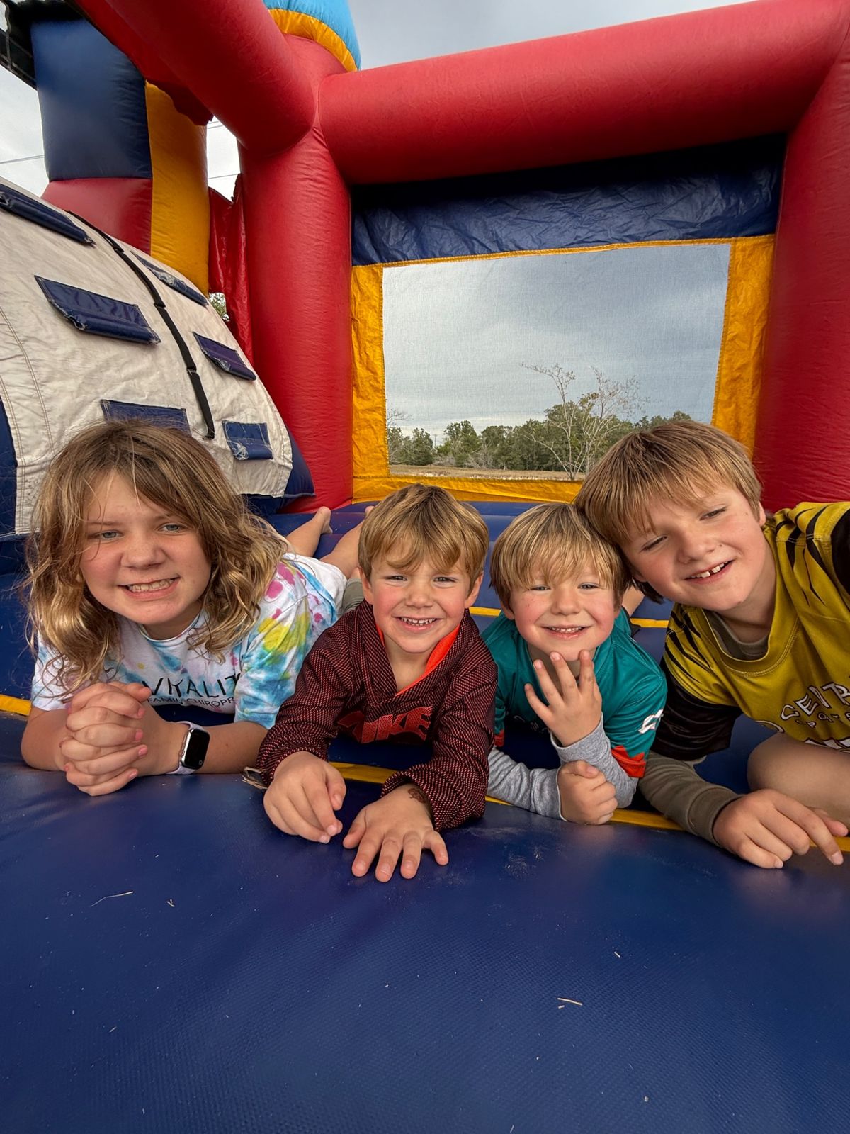 Four kids grinning together inside a bounce house