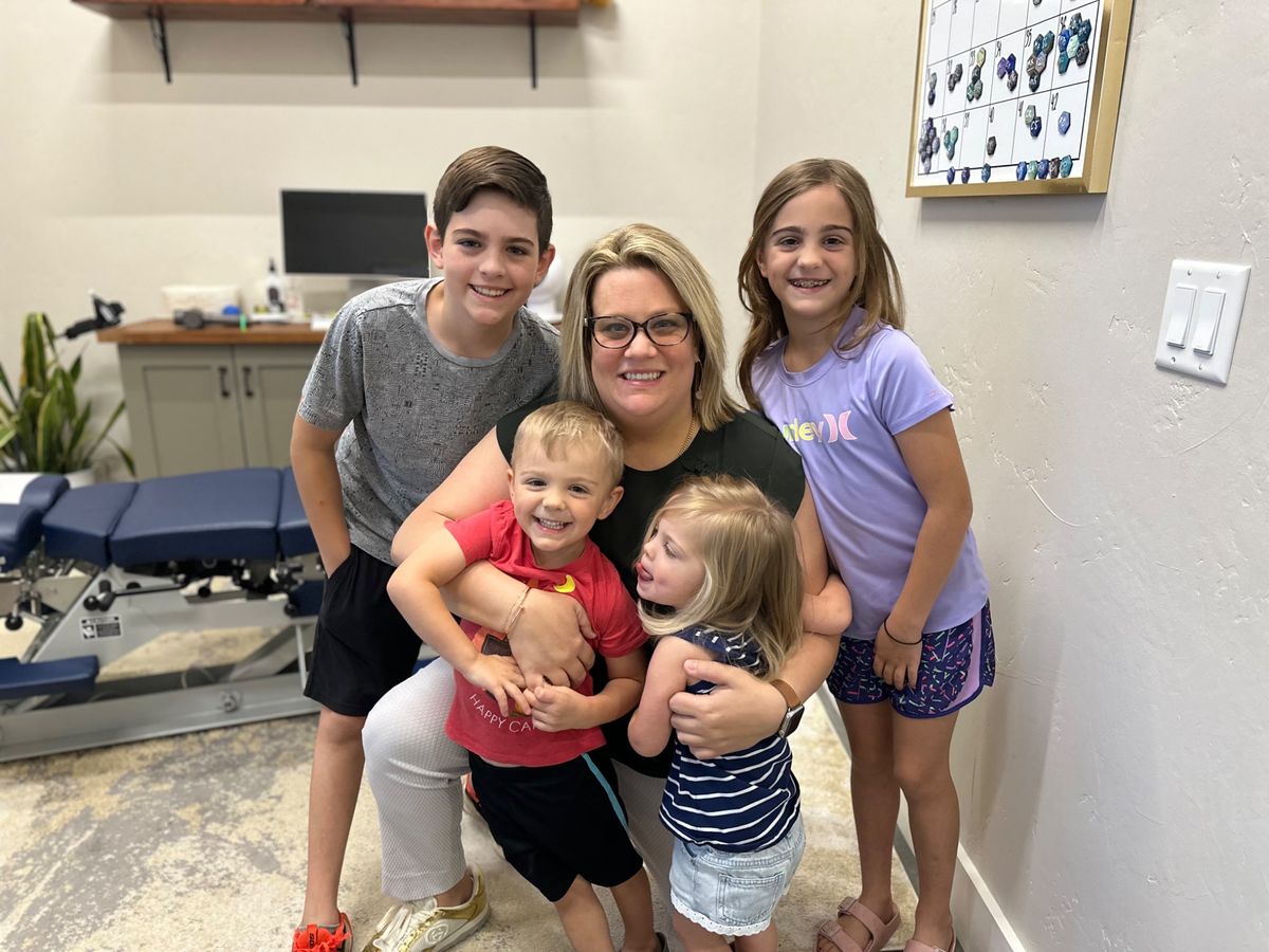 A Vitality chiropractor smiling with a group of children in an adjusting room