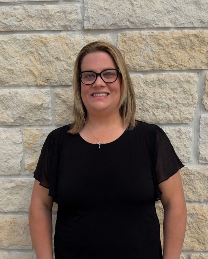 Dr. Christie smiling in front of a stone wall